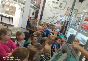 dzieci w muzeum mpk słuchają przewodnika w tle stare zdjęcia