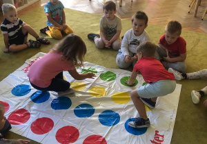 Dzieci stoją na planszy z kolorowymi kropkami