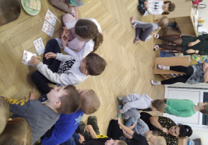 Dzieci na podłodze wykonują zadania związane z Dniem Pluszowego Misia