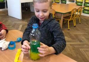 Chłopiec patrzy jaki kolor powstał w jego butelce