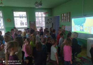 Dzieci stoją i oglądają na tablicy film edukacyjny