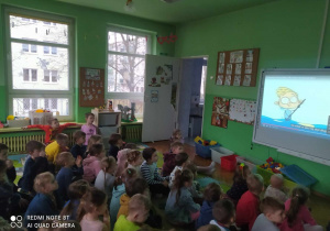 Dzieci siedzą i oglądają film edukacyjny