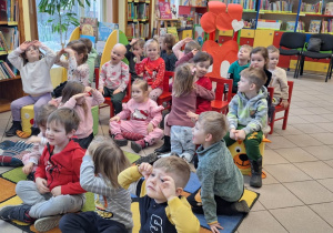 Dzieci są z wizytą w bibliotece. Dookoła widać regały z książkami i kolorowe ściany