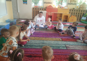 Dzieci siedzą na dywanie, słuchają opowiadania