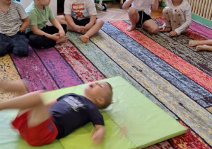 Dzieci ćwiczą na dywanie, materacu i równoważni