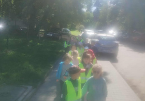 Dzieci są na spacerze. W tle widać zielone drzewa.