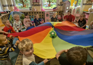 Dzieci podrzucają na chuście piłkę.