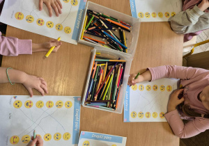 Dzieci łączą kredkami psujące do siebie ikony emocji.