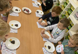 Dzieci siedzą przy stoliku - poczęstunek