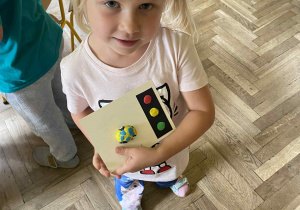 dziewczynka pozuje do zdjęcia z pracą