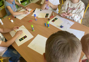 Dzieci siedzą przy stolikach i lepią z plasteliny