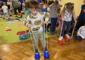 chłopiec wykonuje zadanie - idzie na szczudłach