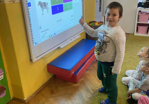 Chłopiec zaznacza na tablicy multimedialnej
