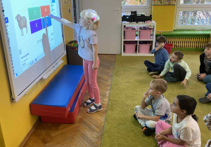Dziewczynka wskazuje odpowiedź na tablicy