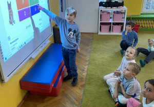 Chłopiec rozwiązuje test na tablicy multimedialnej