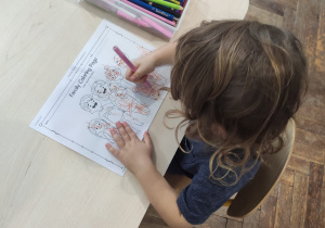 dzieci siedzą przy stoliku i kolorują prace