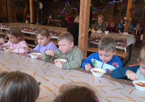 Dzieci biorą udział w warsztatach świątecznych. Robią stroiki i dekorują domki z piernika
