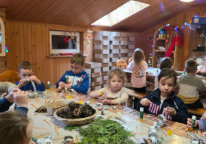 Dzieci biorą udział w warsztatach świątecznych. Robią stroiki i dekorują domki z piernika