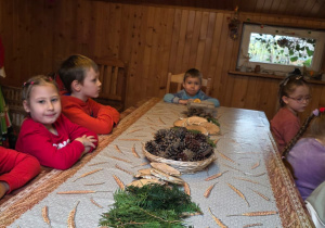 Dzieci biorą udział w warsztatach świątecznych. Robią stroiki i dekorują domki z piernika