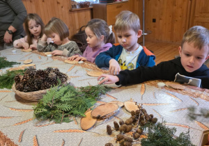 Dzieci biorą udział w warsztatach świątecznych. Robią stroiki i dekorują domki z piernika