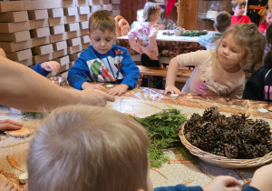 Dzieci biorą udział w warsztatach świątecznych. Robią stroiki i dekorują domki z piernika