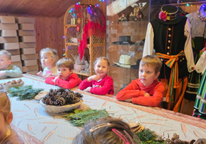 Dzieci biorą udział w warsztatach świątecznych. Robią stroiki i dekorują domki z piernika