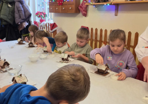 Dzieci biorą udział w warsztatach świątecznych. Robią stroiki i dekorują domki z piernika