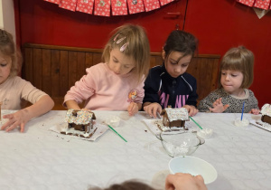 Dzieci biorą udział w warsztatach świątecznych. Robią stroiki i dekorują domki z piernika