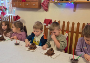Dzieci biorą udział w warsztatach świątecznych. Robią stroiki i dekorują domki z piernika