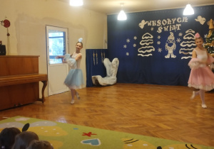 Dzieci siedzą na dywanie i oglądają pokaz tańców z bajek