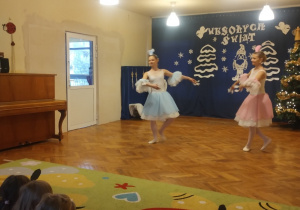 Dzieci siedzą na dywanie i oglądają pokaz tańców z bajek