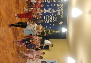 Dzieci siedzą na dywanie i oglądają pokaz tańców z bajek