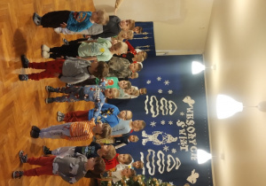 Dzieci siedzą na dywanie i oglądają pokaz tańców z bajek