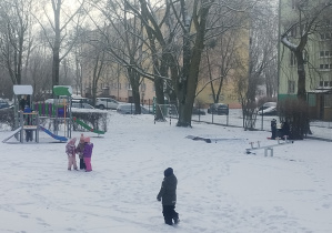 Dzieci w ogrodzie przedszkolnym bawią się na śniegu