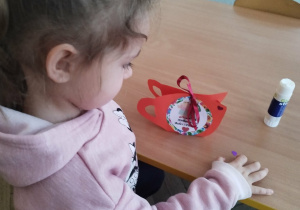 Dziewczynka ozdabia kubeczek serduszkami