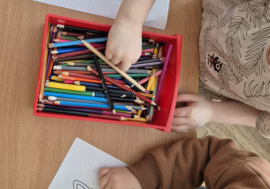 Chłopcy kolorują kredkami sylwety kotów.