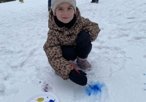 Dziewczynka maluje pędzelkiem po śniegu