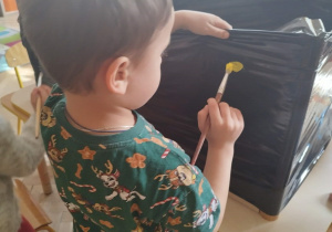 Chłopiec maluje na czarnej foli