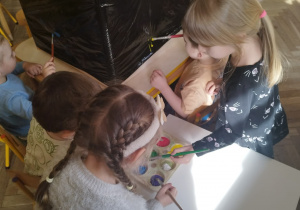 Dziewczynki nabierają farbę potrzebną do malowania na foli