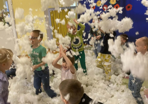 Dzieci podrzucają z radością sztuczny śnieg
