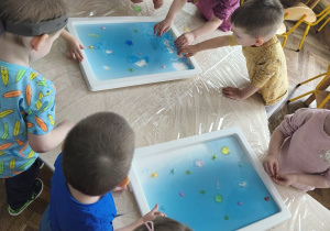 Dzieci wyciągają małe zabawki zatopione w galaretce.