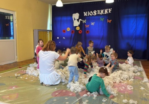 Dzieci bawią się białymi piórkami.