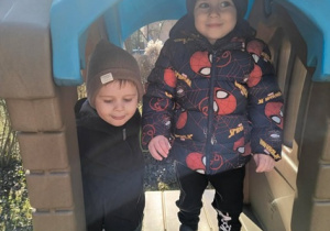 Chłopcy bawia się w plastikowym zamku.