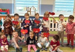 Dzieci pozują do zdjęcia z własnoręcznie zrobionymi serduszkami.