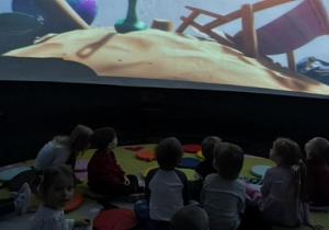 Dzieci oglądają bajkę edukacyjną pod kopuła.