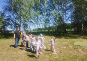 Dzieci spędzają czas na świeżym powietrzu w czasie wycieczki. Bawią się i biorą udział w warsztatach.