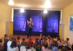Dzieci siedzą na dywanie i słuchają koncertu