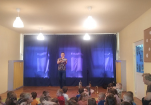 Dzieci siedzą na dywanie i słuchają koncertu