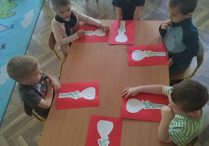 Dzieci siedzą przy stoliku będą wykonywać pracę plastyczną