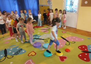 Dzieci na dywanie bawią się chustą animacyjna i na krążkach